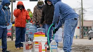 Houston residents fill up water from an outdoor hose after power outages and water shortage from the winter storm. 