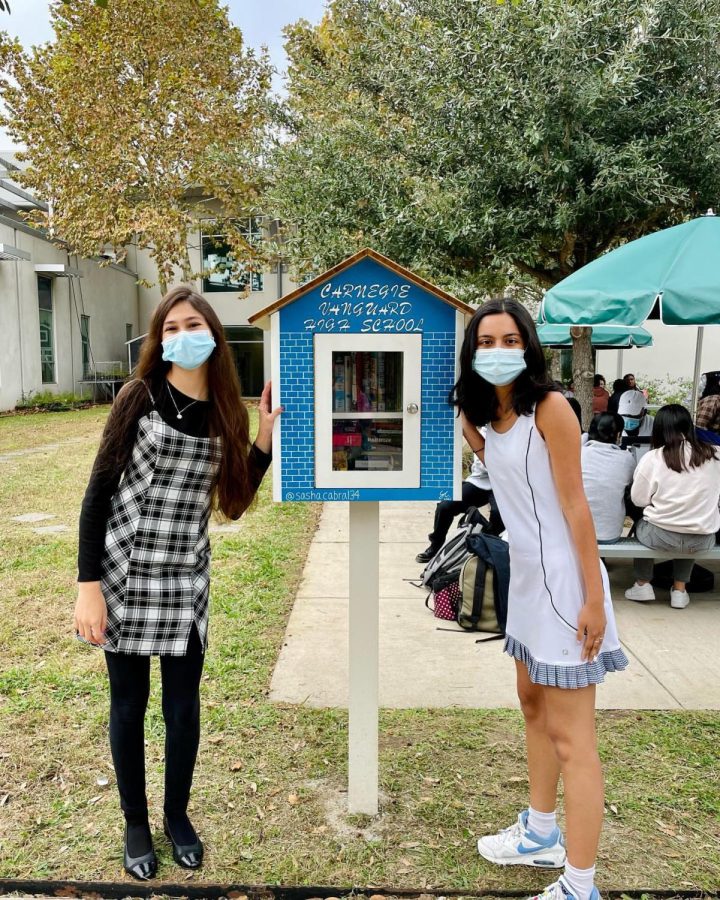 Cabral (left) and Fernandez (right) show off the Little Free Library located in the courtyard. 