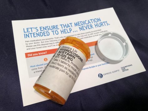 A prescription pill bottle for hydrocodone and a flyer that warns of opioids dangers.