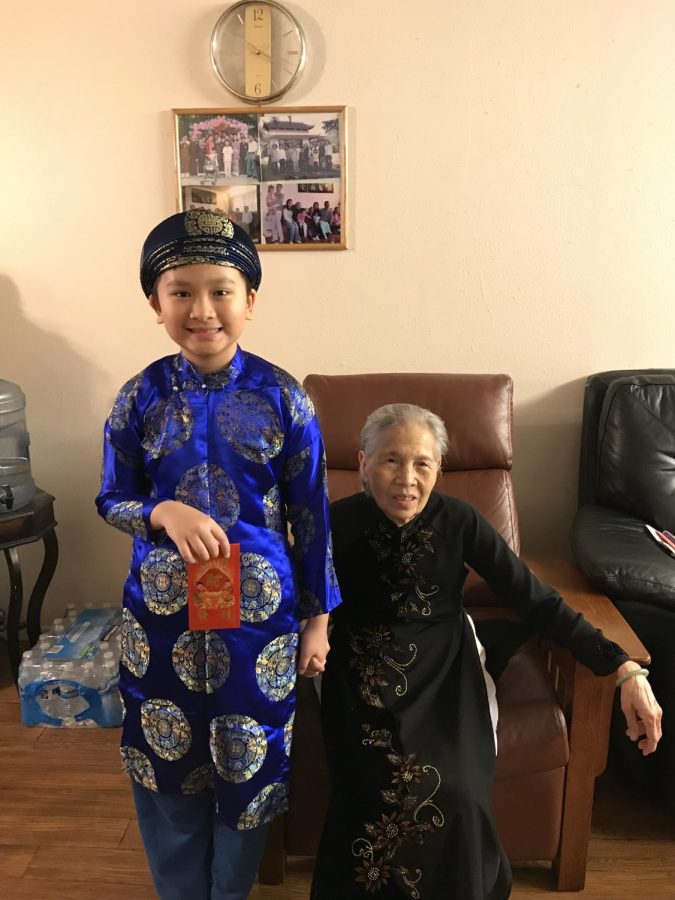 John Nguyen wearing a traditional Vietnamese áo dài next to his grandmother on Lunar New Year. 