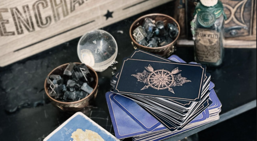 An assortment of tarot cards and crystals on a desk with various other spiritual accessories.