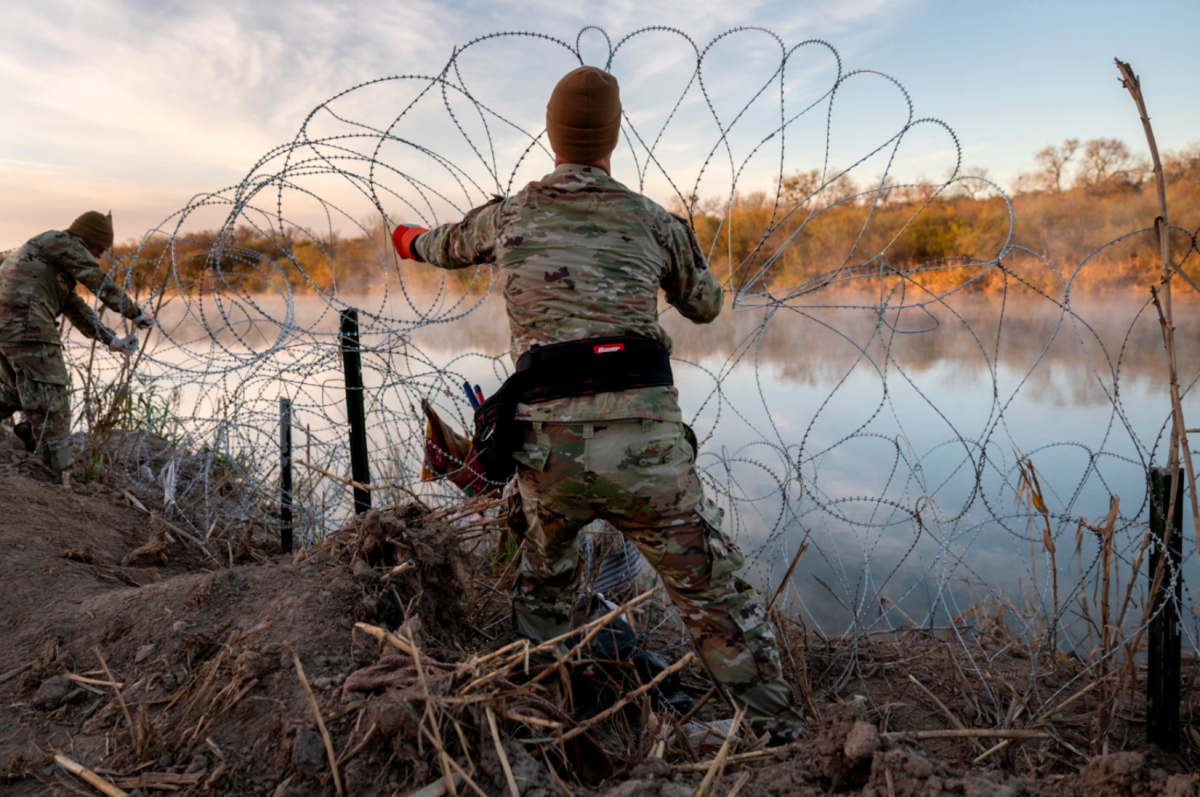 A border patrol agent placing razor wire at the border