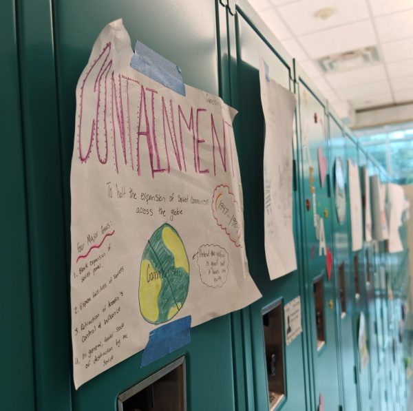 Papers explaining containment and other key terms hang against the lockers. Nathan Wendt uses the gallery walk activity to review vocabulary. 