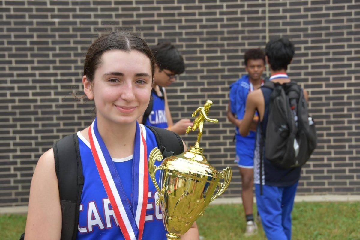 On October 5, 2024. Jenny Dietz wears her medal and holds the team trophy after a cross country Districts meet.