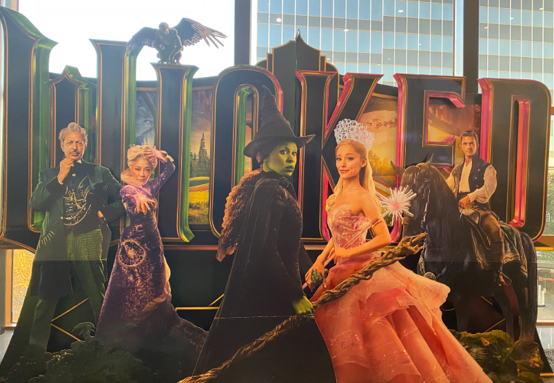 A life-sized standee of the "Wicked" main characters at a theatre.