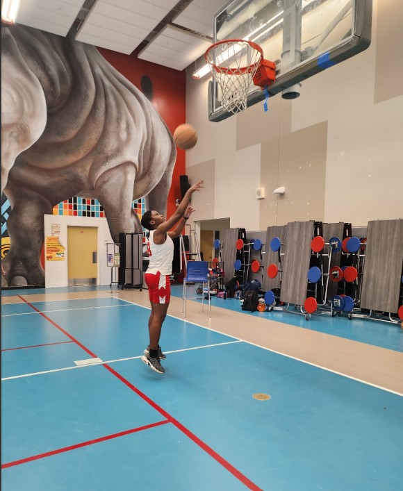 Aretha captured in mid-air making a lay up on the basketball court.