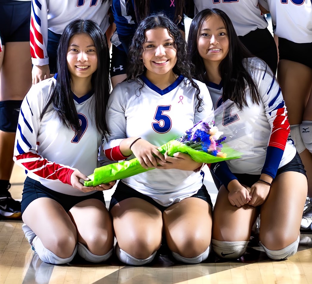 Sarah Ramos, center, poses for a photo on the volleyball court.